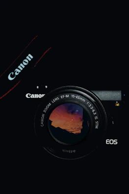 A sleek modern mirrorless camera with a colorful lens reflecting a sunset.