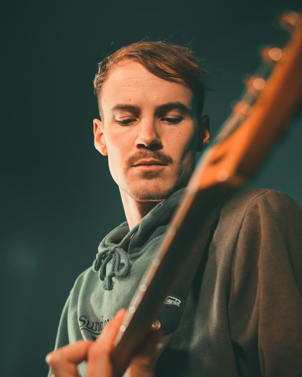 man in gray coat holding brown electric guitar