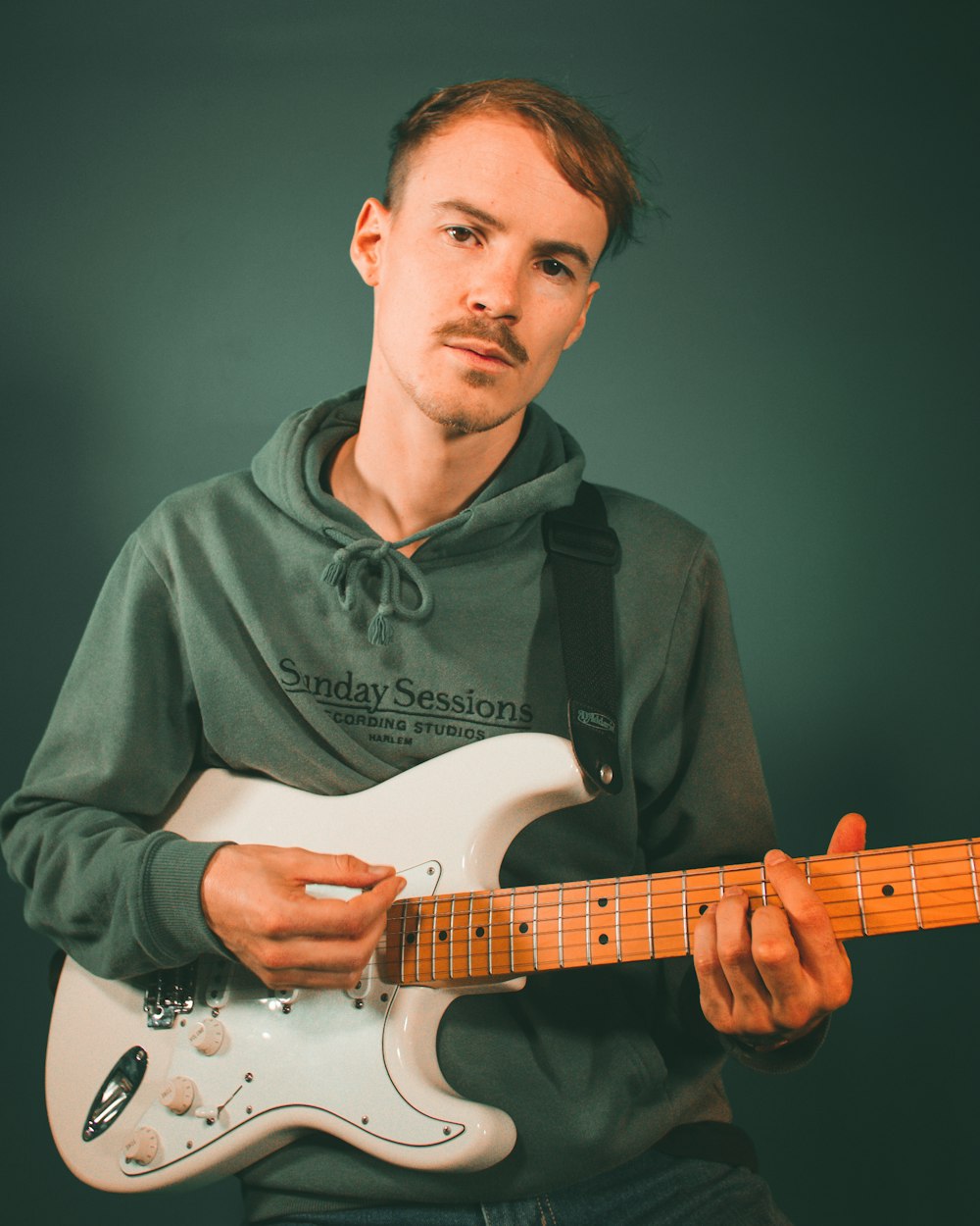 man in black button up shirt playing white stratocaster electric guitar