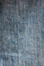 Close-up of soft indigo denim fabric texture with detailed stitching.