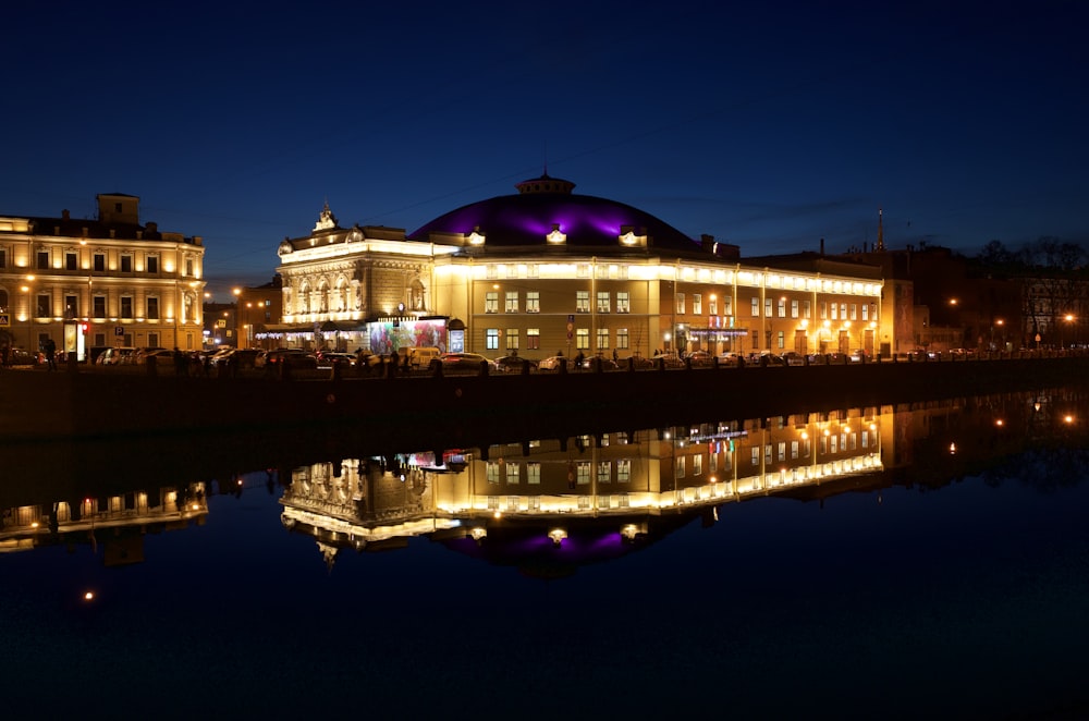 bâtiment éclairé près d’un plan d’eau pendant la nuit