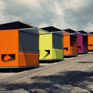 A row of container shops set up in a community market, each with unique branding and inviting entrances.