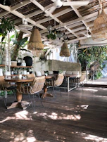 Cozy café terrace with rustic wooden tables and golden light filtering through trees.