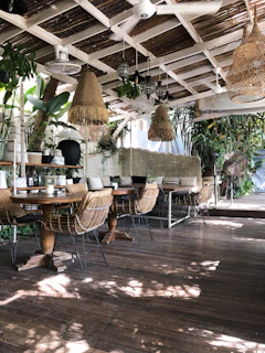 Cozy café terrace with rustic wooden tables and golden light filtering through trees.