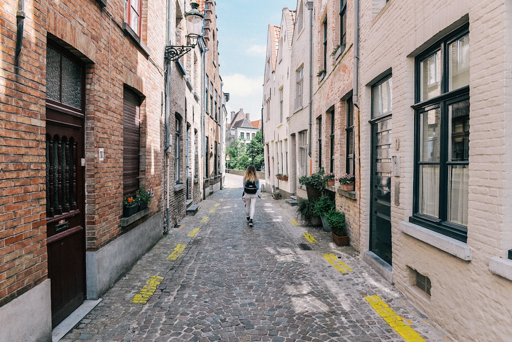 woman in black jacket walking on sidewalk during daytime