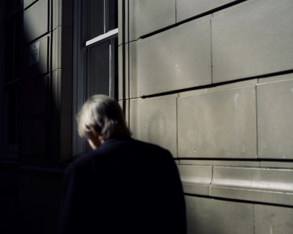 man in black suit standing near window