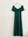 An elegant party dress displayed on a hanger against a pastel-colored wall.