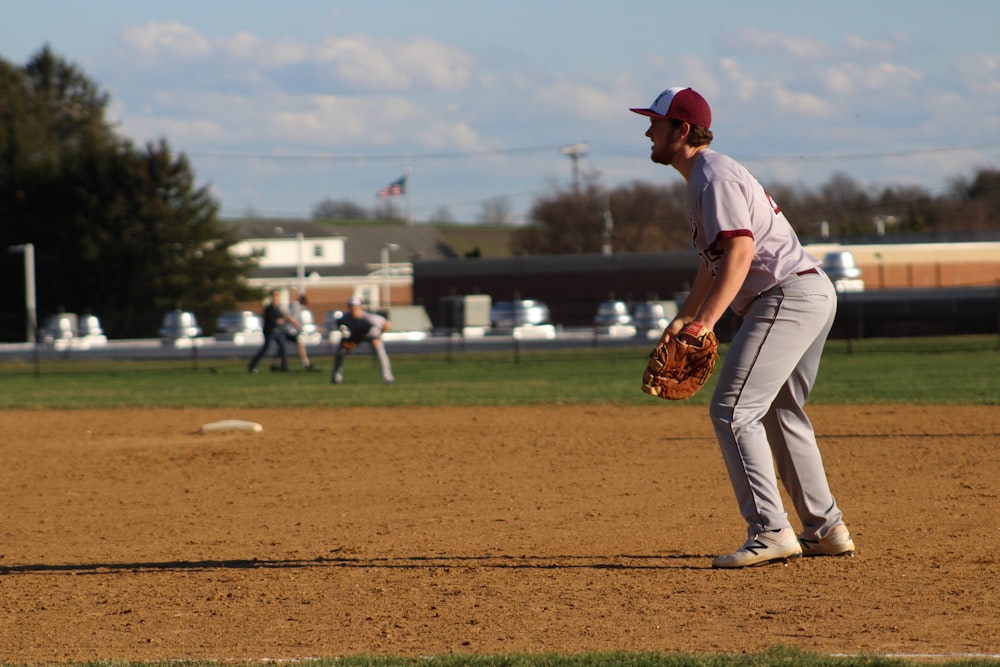 Uomo in maglia da baseball rossa e pantaloni bianchi in piedi sul campo durante il giorno