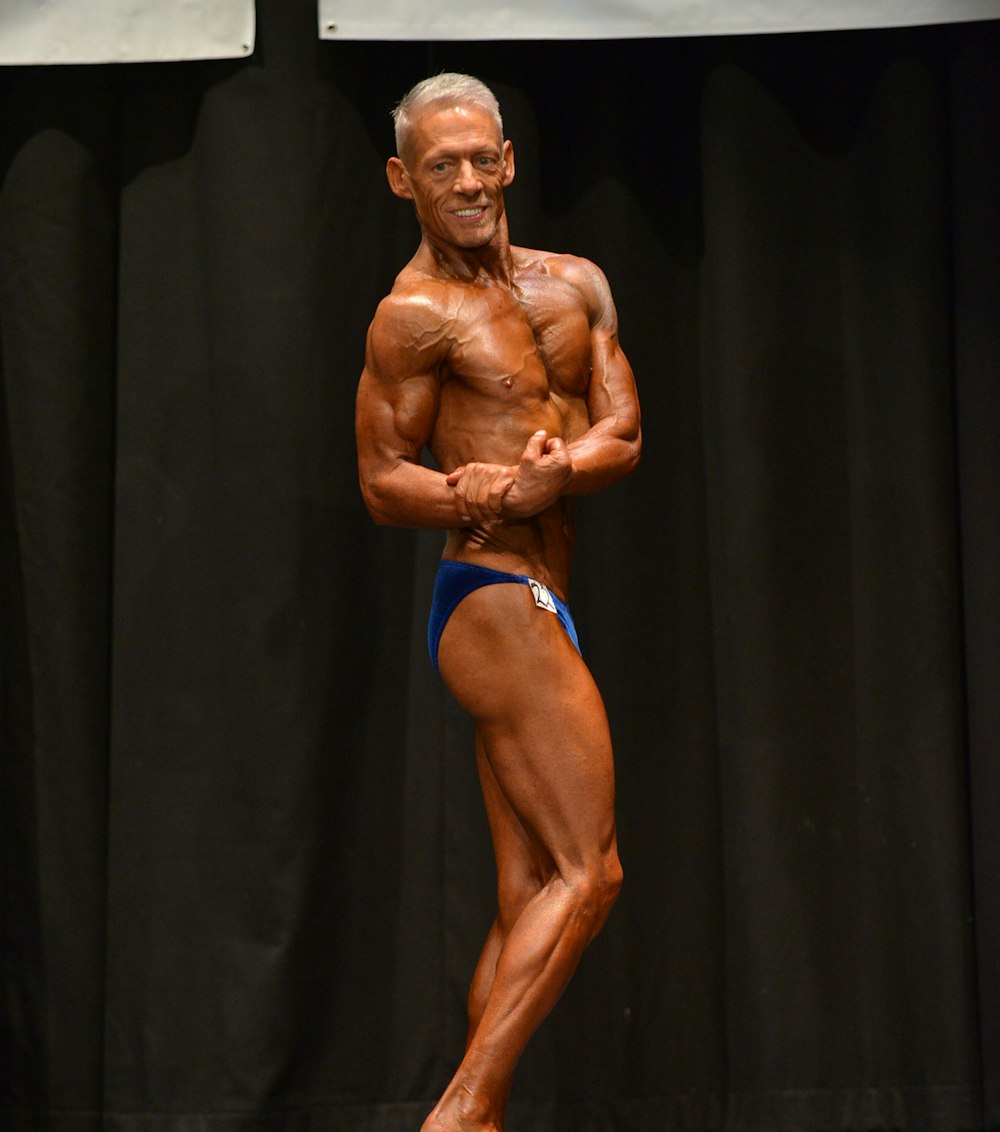 man in blue brief standing on black textile