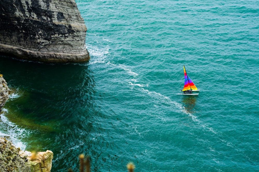 yellow and red kayak on sea near brown rock formation during daytime