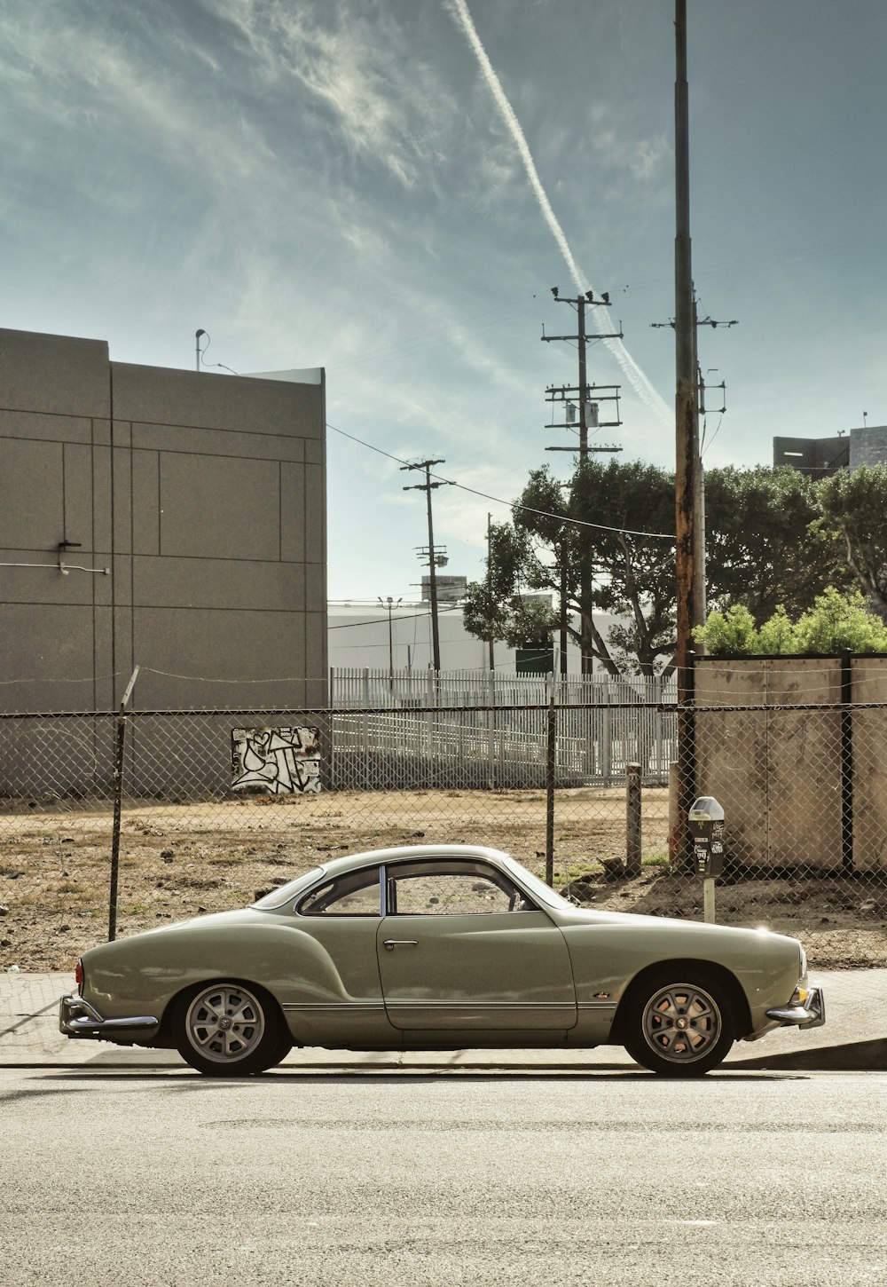 silver coupe parked beside gray metal fence