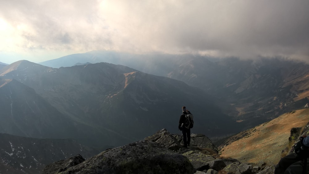 검은 재킷을 입은 남자가 낮에 바위 산에 서 있습니다.