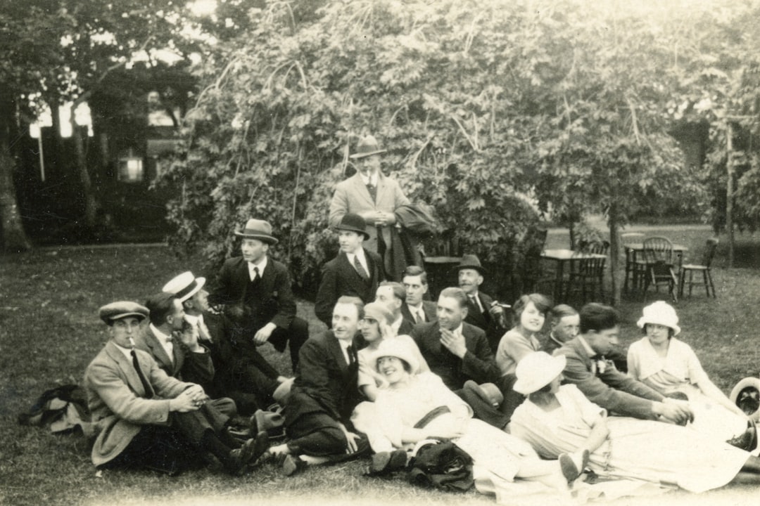 grayscale photo of people sitting on grass field