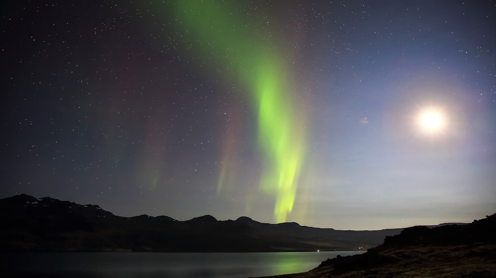 green aurora lights over the lake during night time