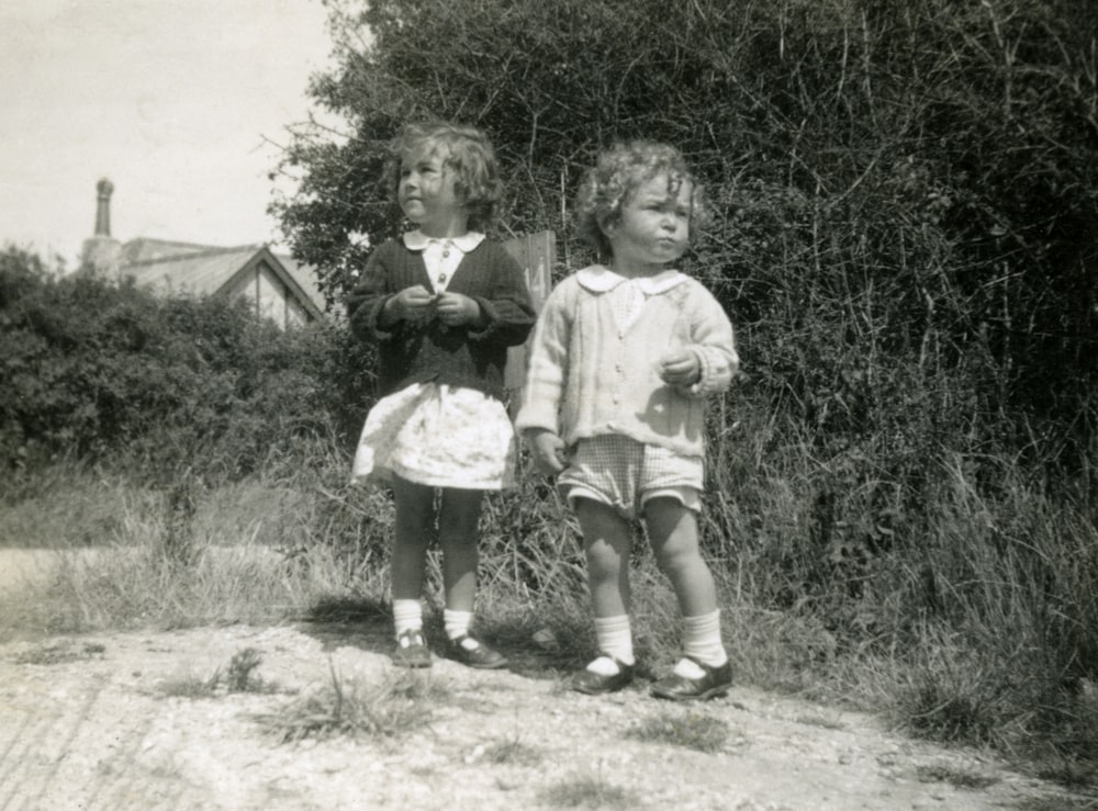 grayscale photo of 2 boys and girl holding umbrella