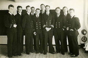 Smiling veterans standing side by side on a wooden pier overlooking the water.