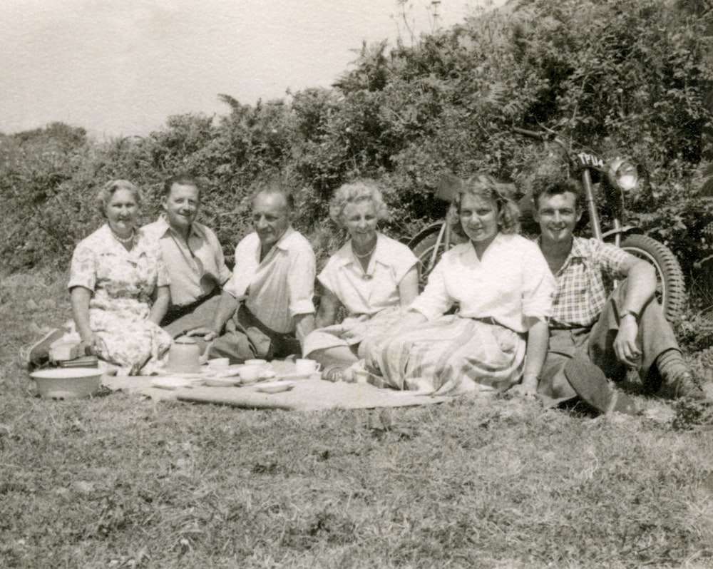 grayscale photo of group of men sitting on grass