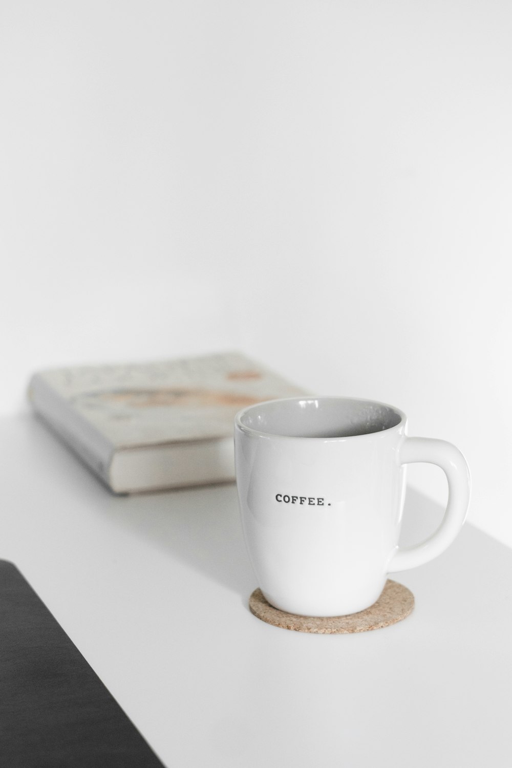 white ceramic mug beside brown wooden board on white table