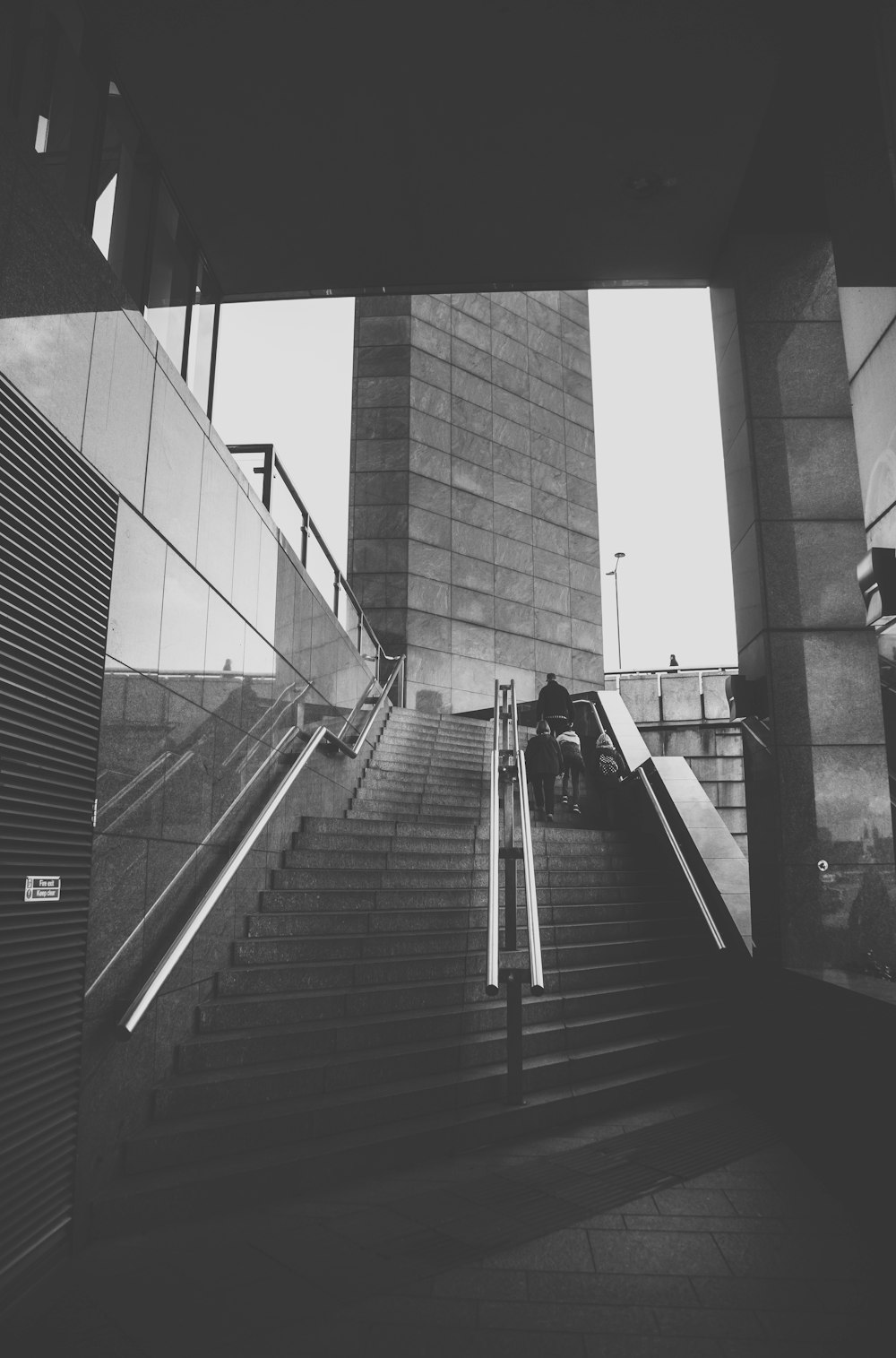 grayscale photo of staircase in front of brick wall