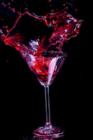 A cinematic shot of a cocktail being poured, with rich reds and deep shadows.