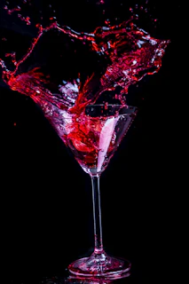 A cinematic shot of a cocktail being poured, with rich reds and deep shadows.