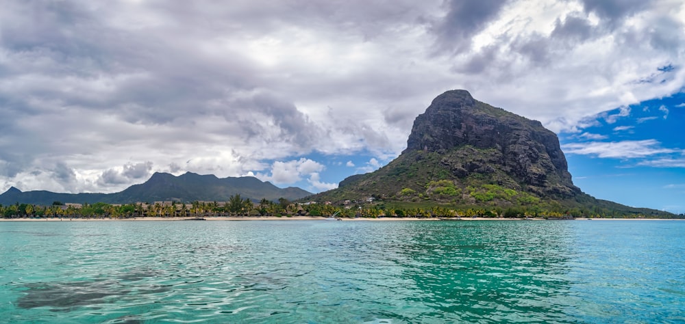 green mountain beside body of water under cloudy sky during daytime