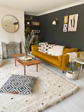 Cozy living room corner with sage green accents and terracotta cushions on a cream sofa.