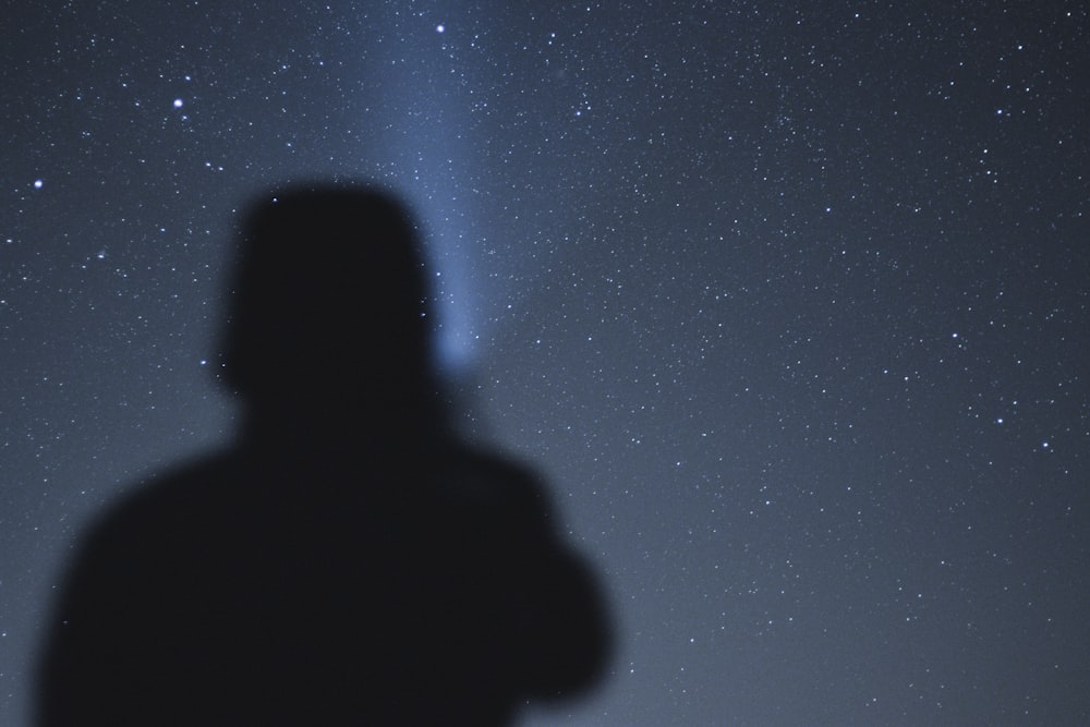 silhouette of man under starry night