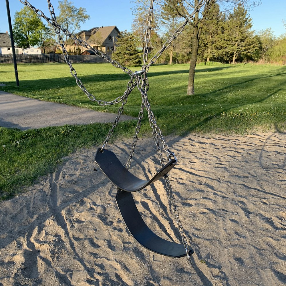 black swing on brown sand during daytime