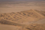 A panoramic view of a desert landscape with sand dunes stretching into the horizon.