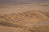 Expansive desert dunes stretching toward a golden sunset horizon.
