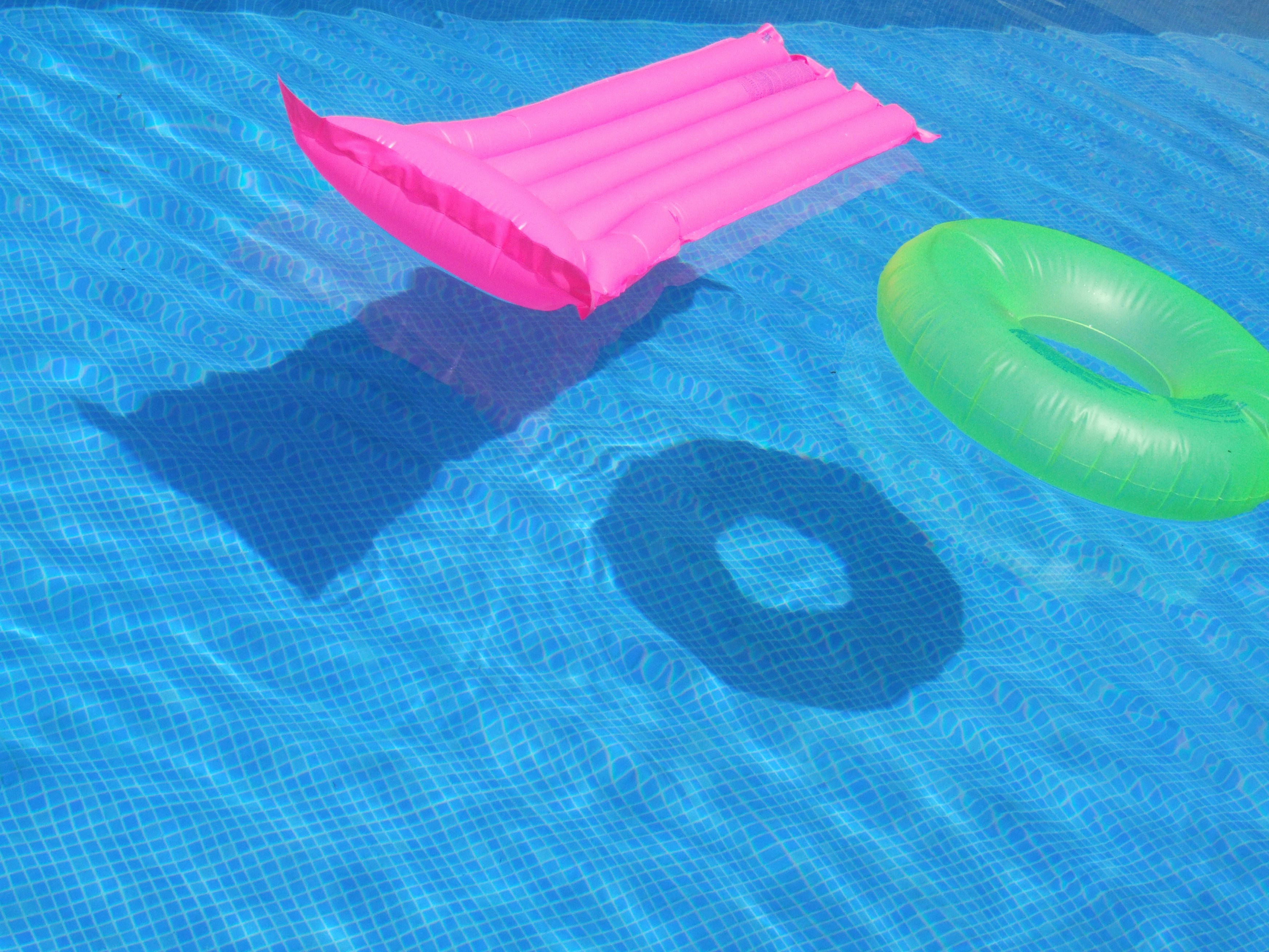 Bright green inflatable avocado pool float in a sparkling blue swimming pool on a sunny day