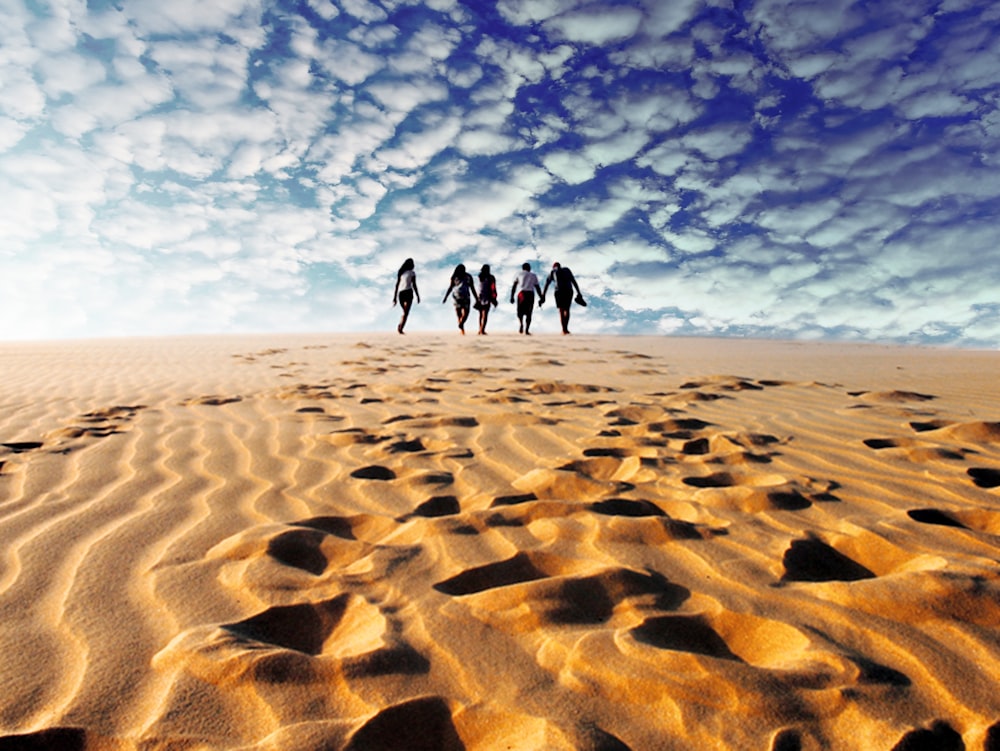 personas que caminan sobre arena marrón bajo el cielo azul durante el día