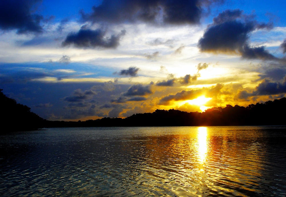 body of water under cloudy sky during sunset