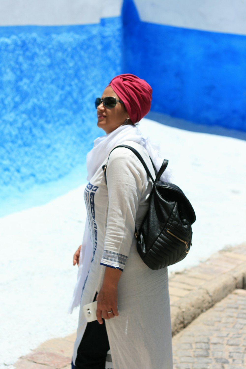 Mujer con chaqueta blanca y gorro de punto rojo de pie sobre arena blanca durante el día