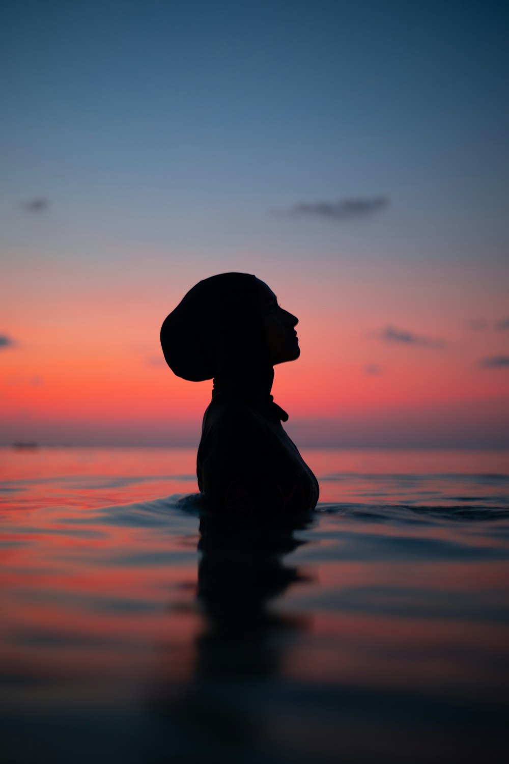 Silhouette einer Frau mit Sonnenhut auf dem Wasser während des Sonnenuntergangs