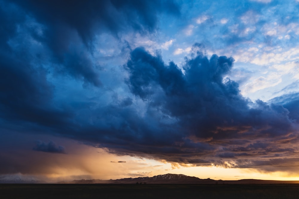 silhouette of mountain under cloudy sky during sunset