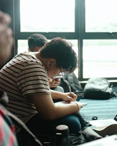A student happily taking notes during an online tutoring session in a cozy home setting.