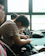 A focused student writing notes during an online tutoring session in a bright, organized study space.