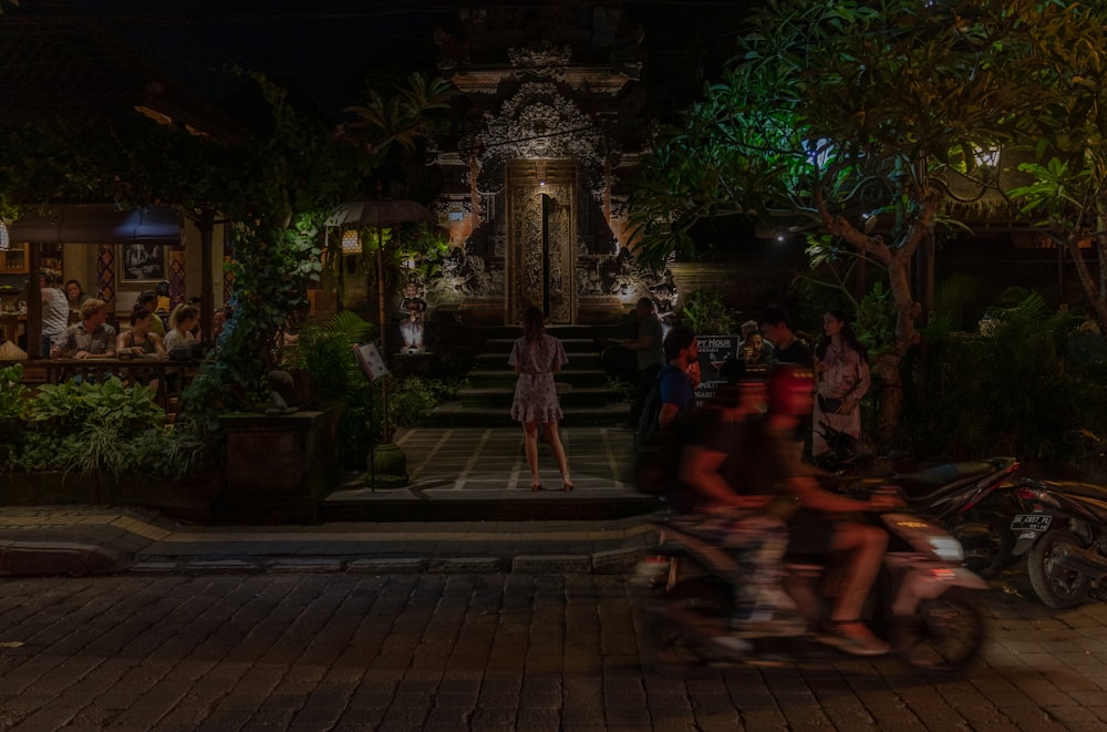 people sitting on brown wooden bench near water fountain during night time