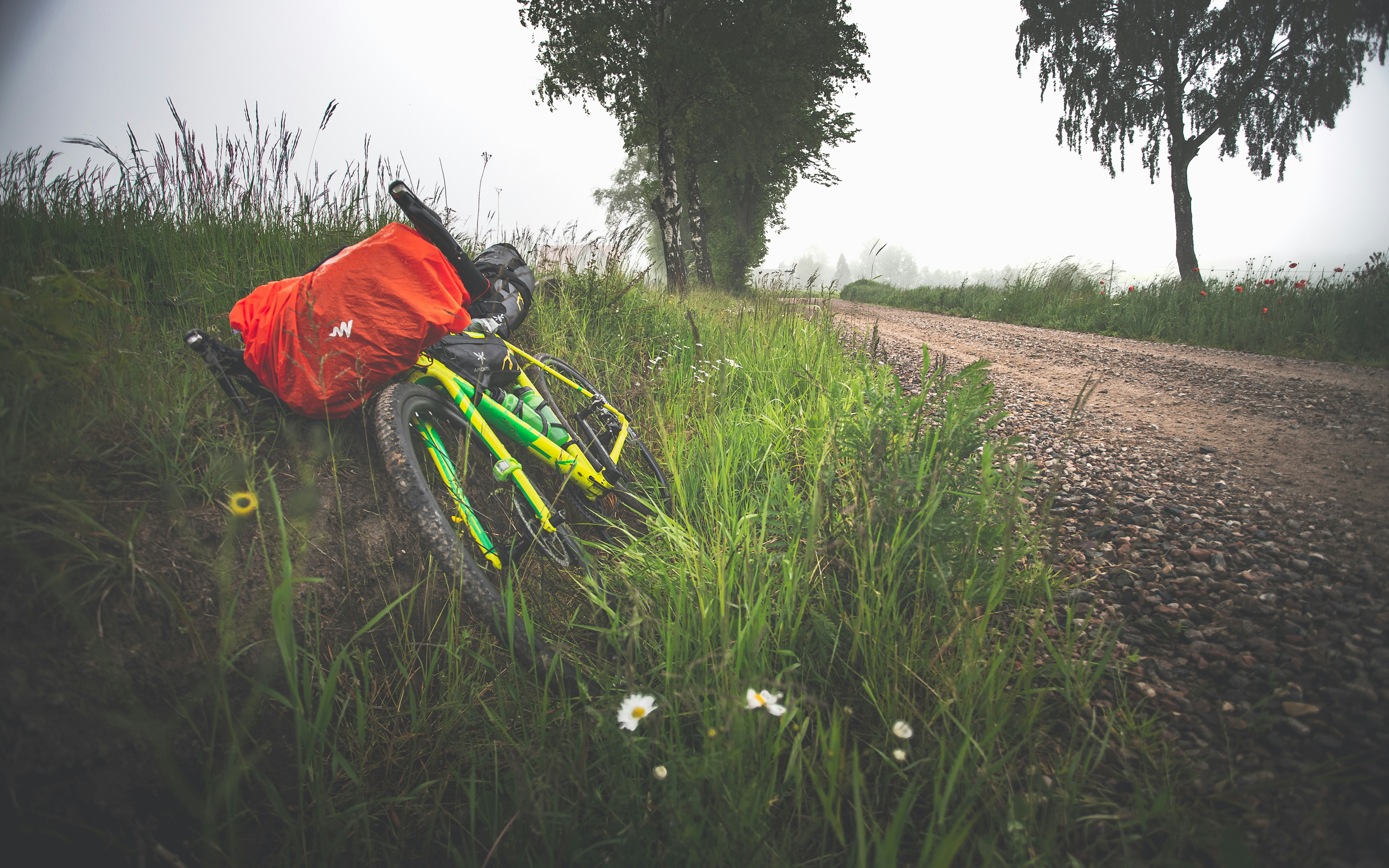 person in red jacket and black pants riding green bicycle on dirt road during daytime