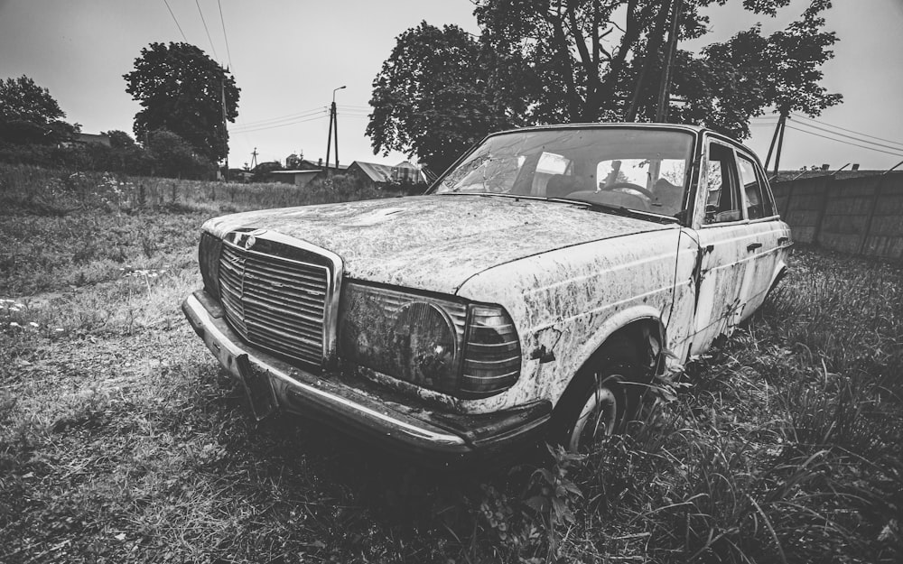 grayscale photo of car near trees