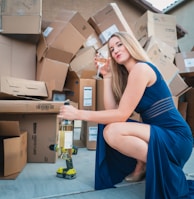 woman in blue sleeveless dress sitting on brown cardboard box