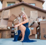 woman in blue dress holding brown cardboard box