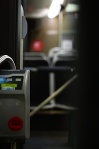 A close-up image of a ticket validation machine inside an empty public bus, with rows of unoccupied seats visible in the background. The lighting is dim, suggesting nighttime or evening.