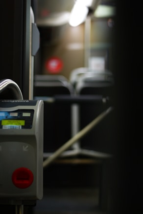 A close-up image of a ticket validation machine inside an empty public bus, with rows of unoccupied seats visible in the background. The lighting is dim, suggesting nighttime or evening.