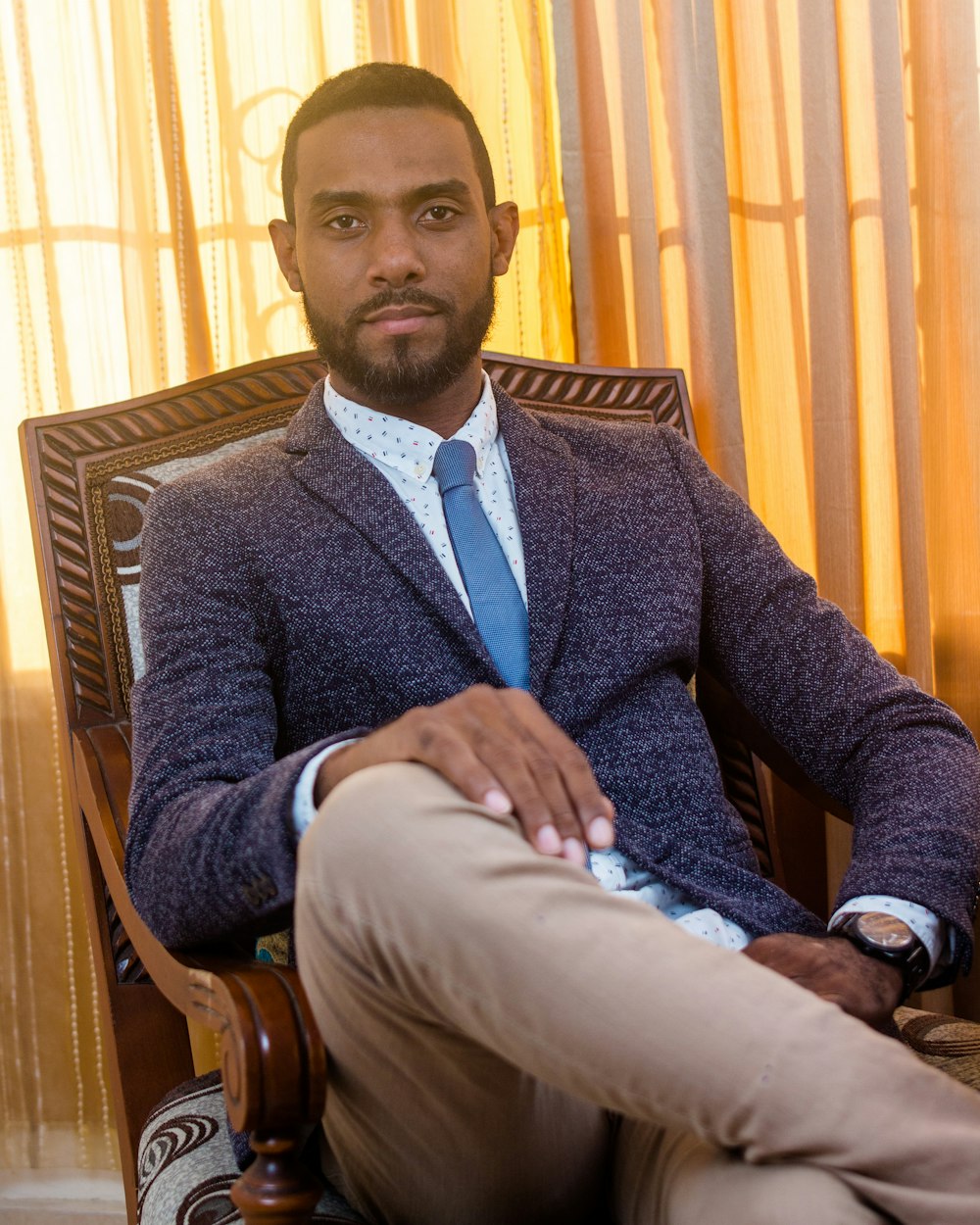 man in black suit sitting on brown wooden armchair