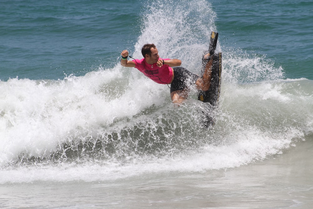 man in red shirt surfing on sea waves during daytime