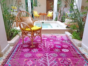 A cozy living room corner featuring a vibrant artificial cedar topiary beside a soft pink rug.