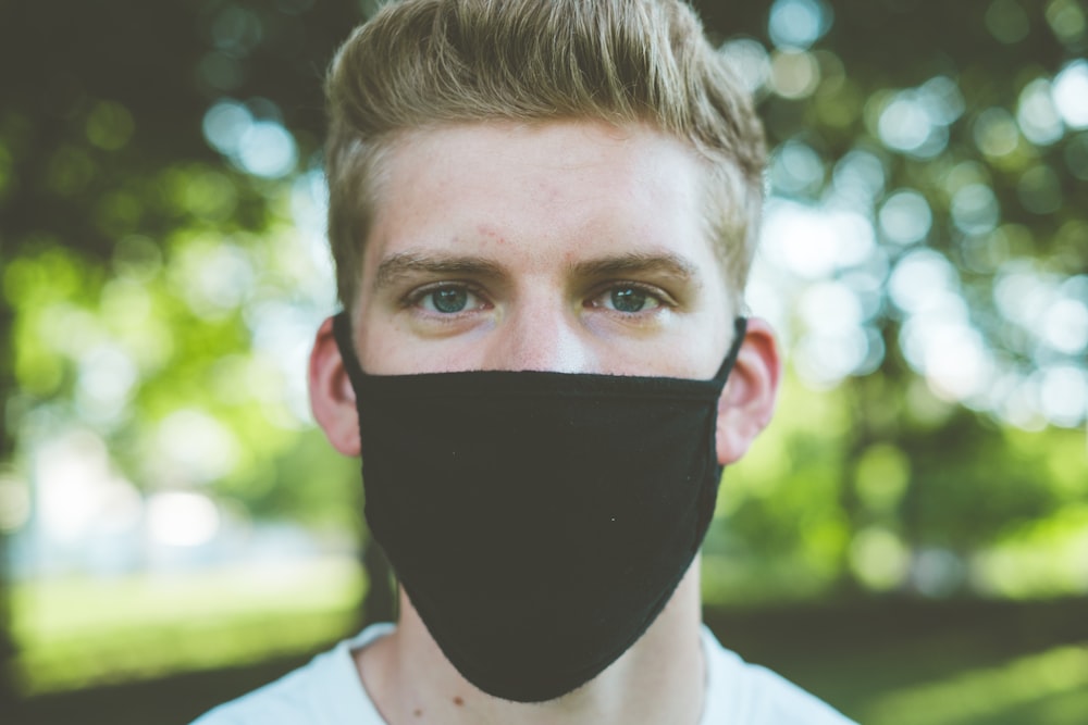 boy in white shirt covering his face with black mask